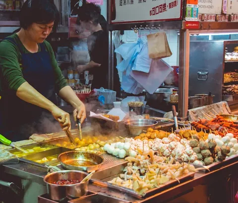 A night market food stall with skewers and steam.